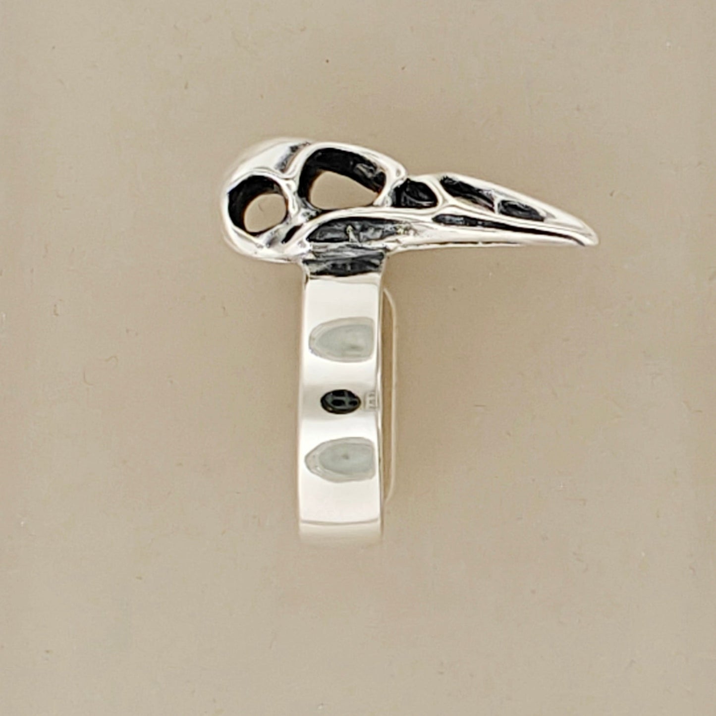 Close-up of side of handcrafted raven skull ring in silver bronze or steel