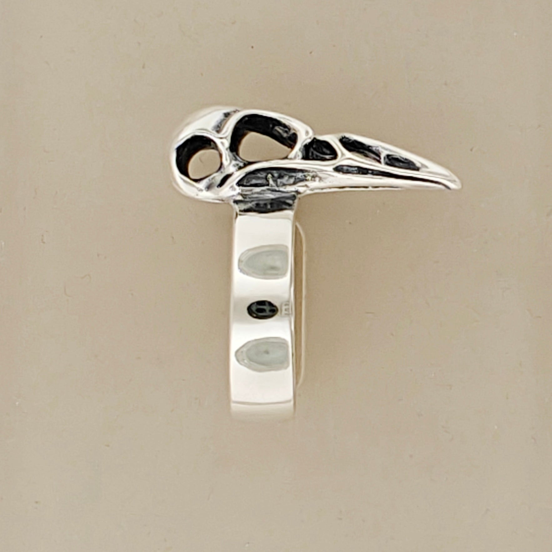 Close-up of side of handcrafted raven skull ring in silver bronze or steel