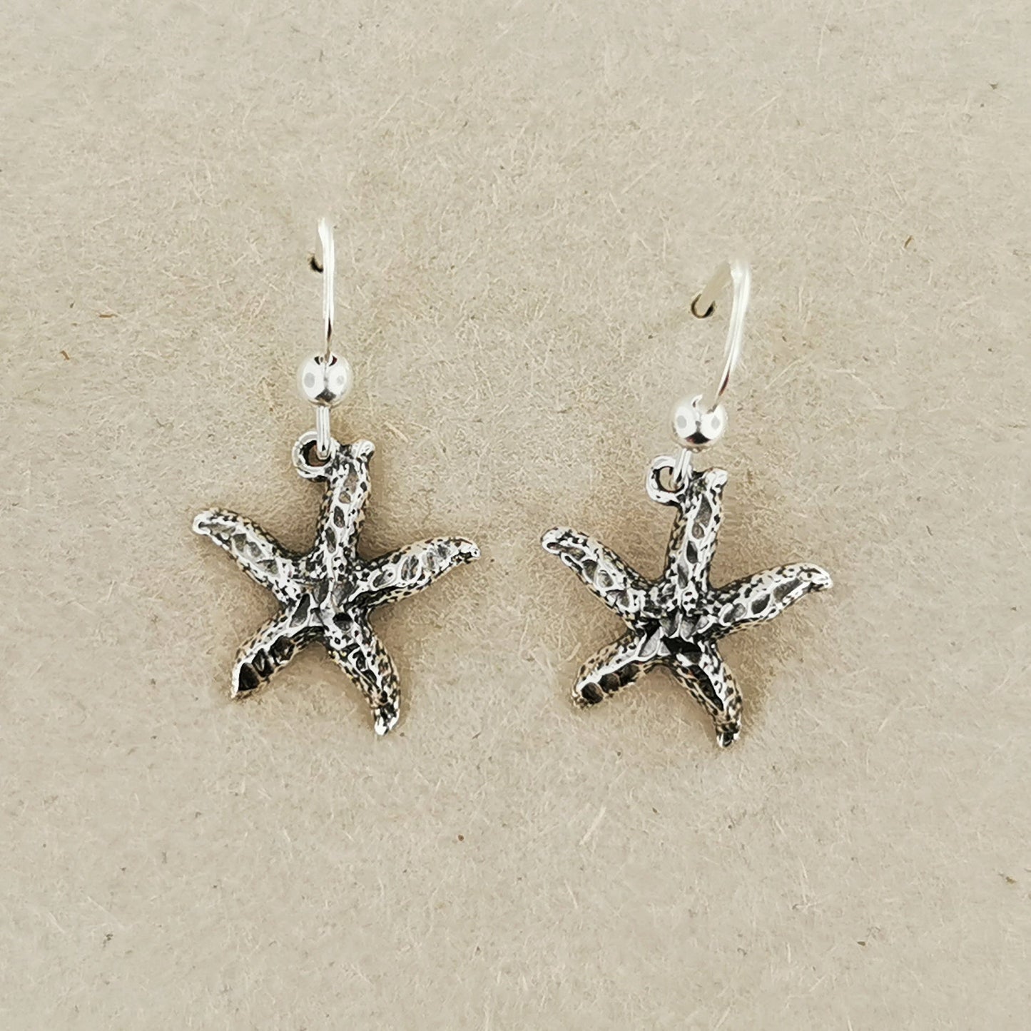 Close-up of silver starfish earrings with beachy charm and style