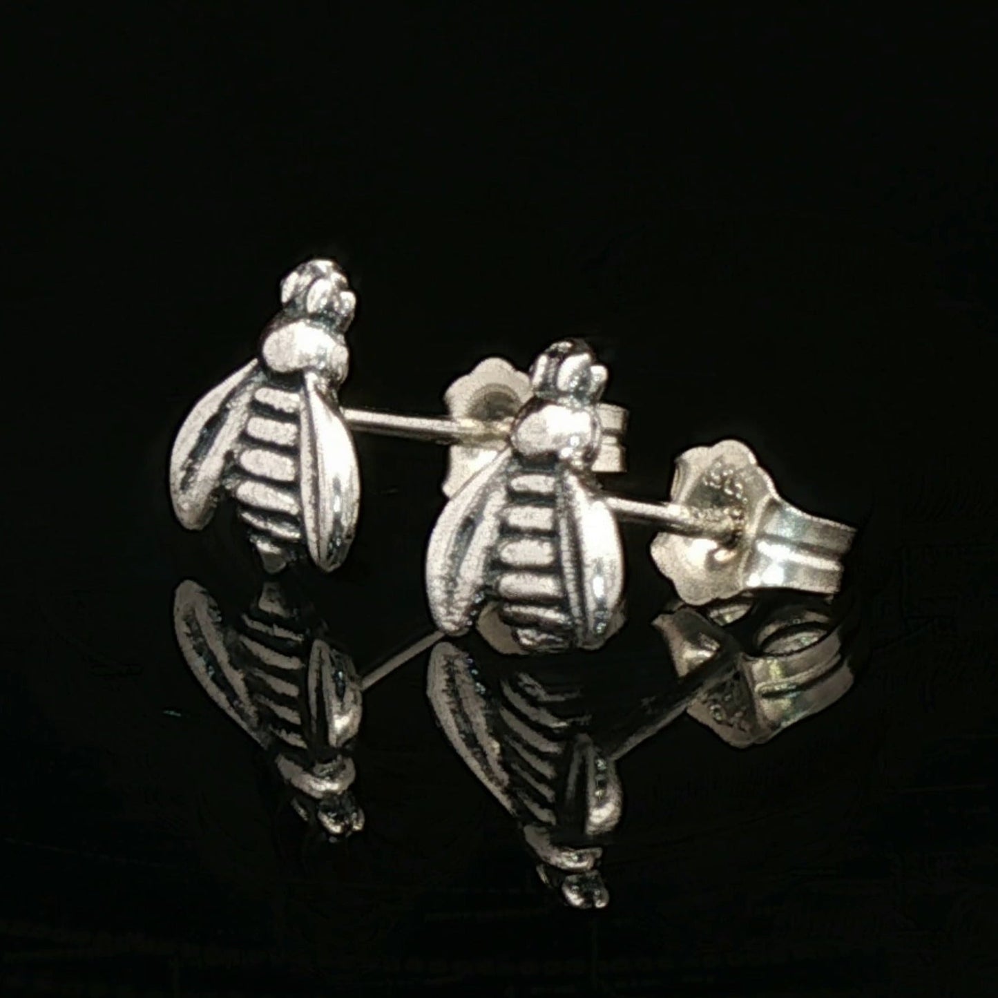 Silver bee-shaped earrings on a black background