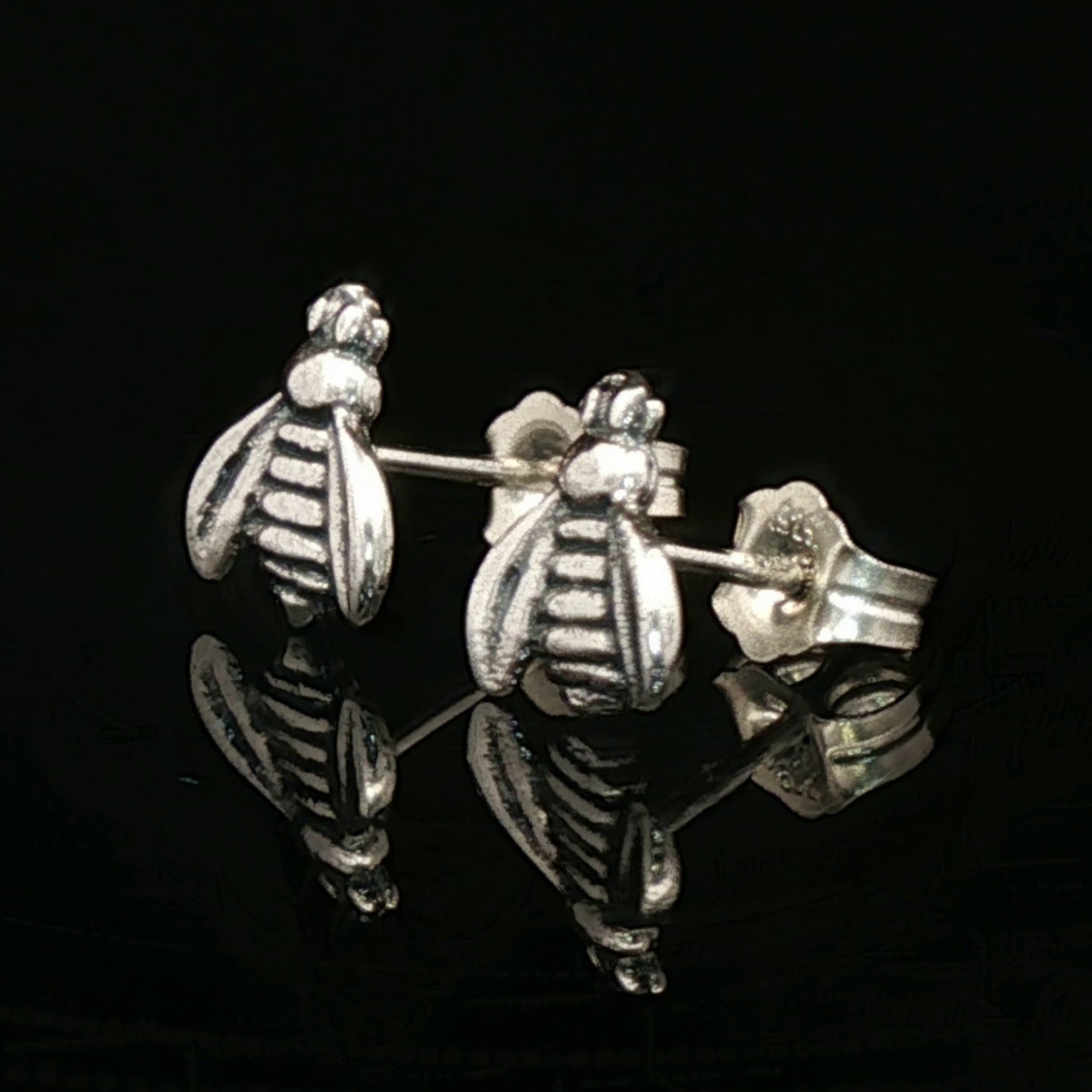 Silver bee-shaped earrings on a black background