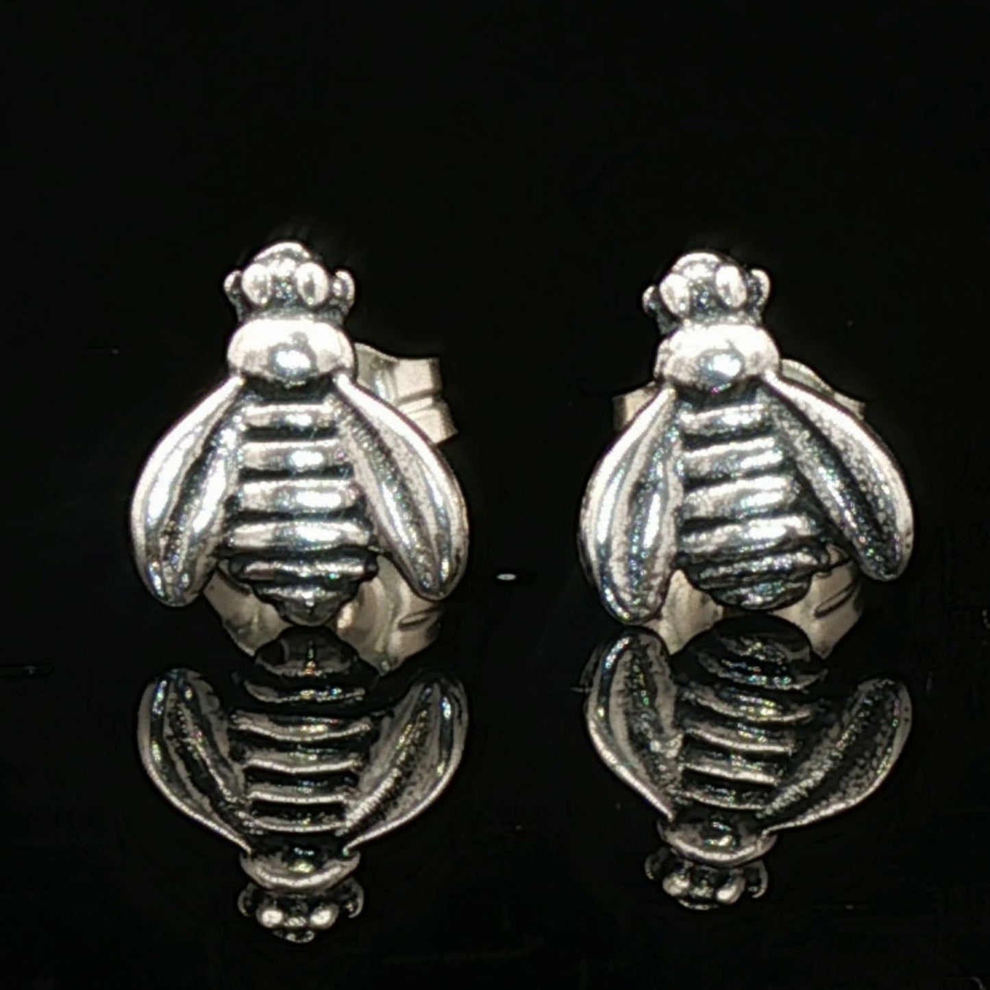 Silver bee-shaped earrings on a black background