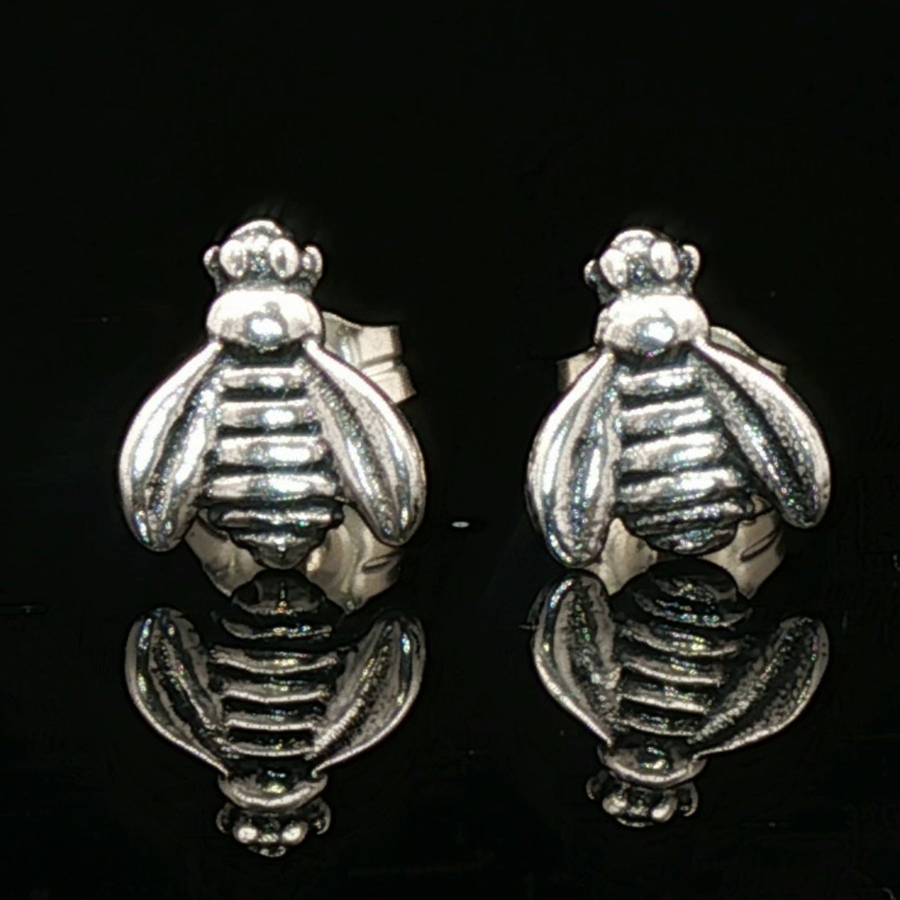 Silver bee-shaped earrings on a black background