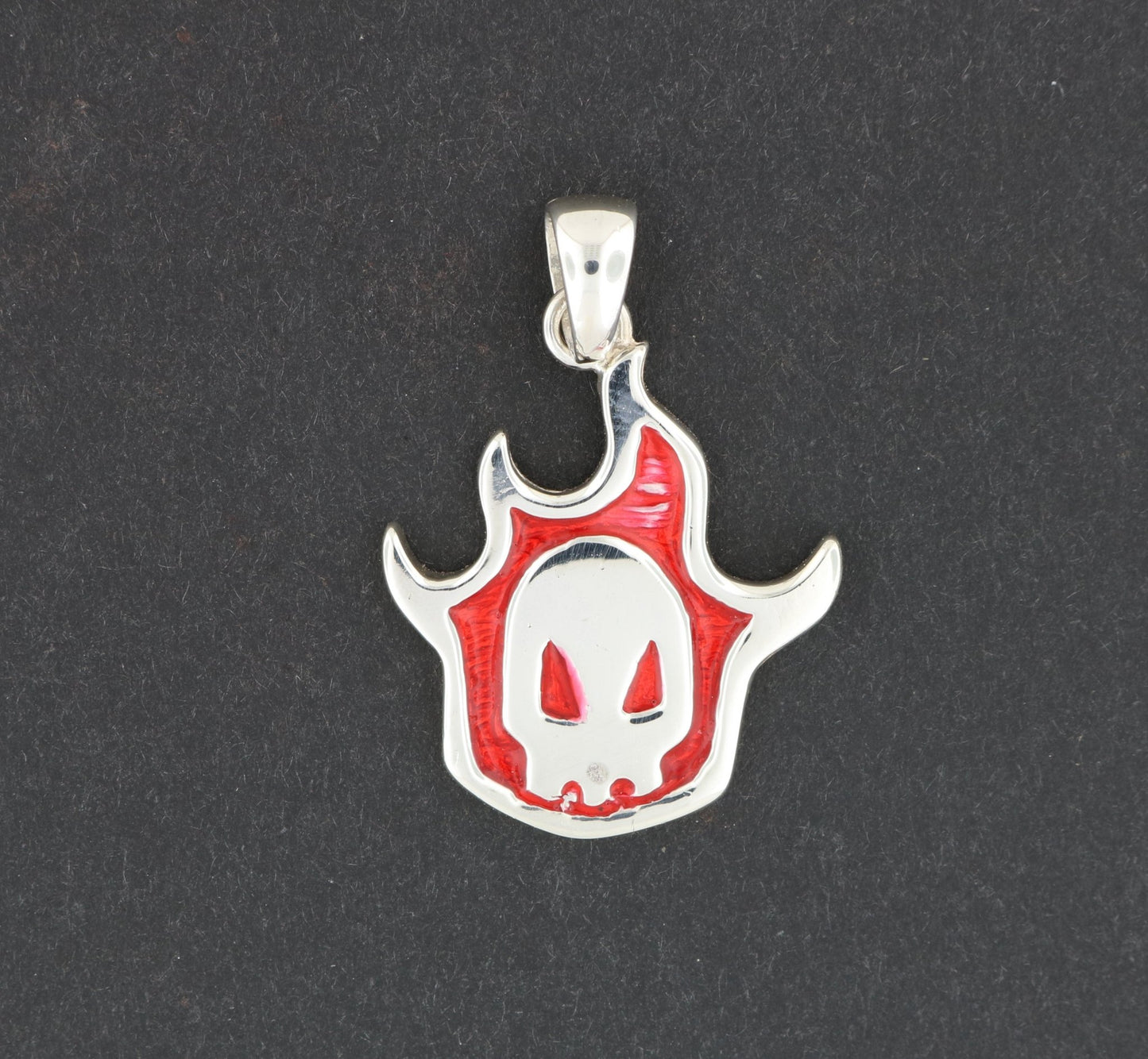 A silver pendant in the shape of a skull with a red flame design.