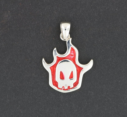 A silver pendant in the shape of a skull with a red flame design.