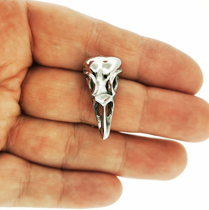 Silver bird skull pendant held in a hand against a white background. Dark aesthetic bird skull charm for fans of witchcraft and alt fashion