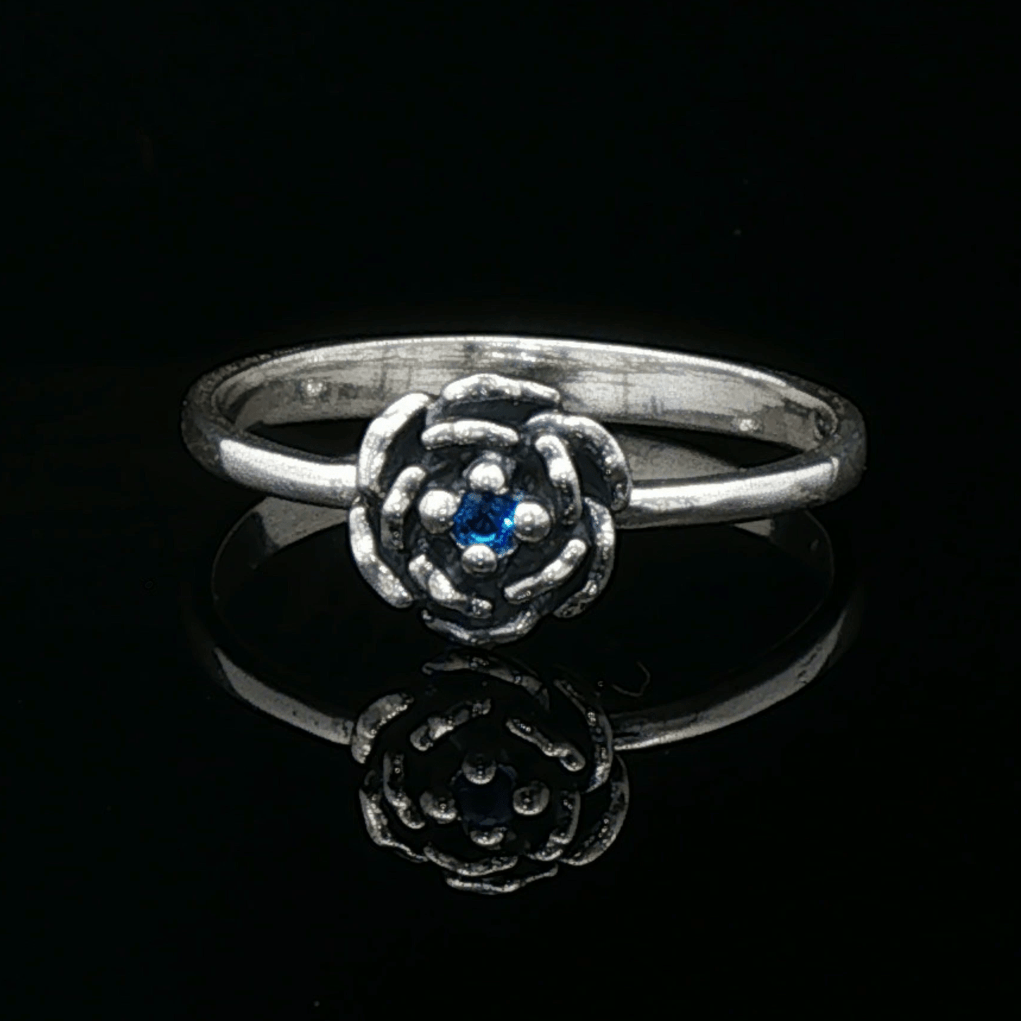 Handmade Small Rose Ring in .925 Sterling Silver featuring a delicate sculpted rose with a 1.5mm coloured cubic zirconia birthstone at its centre. Elegant and dainty yet durable, this floral ring makes a perfect gift of love, promise, or self-expression. Crafted by Le Dragon Argenté in Montreal, Canada.
