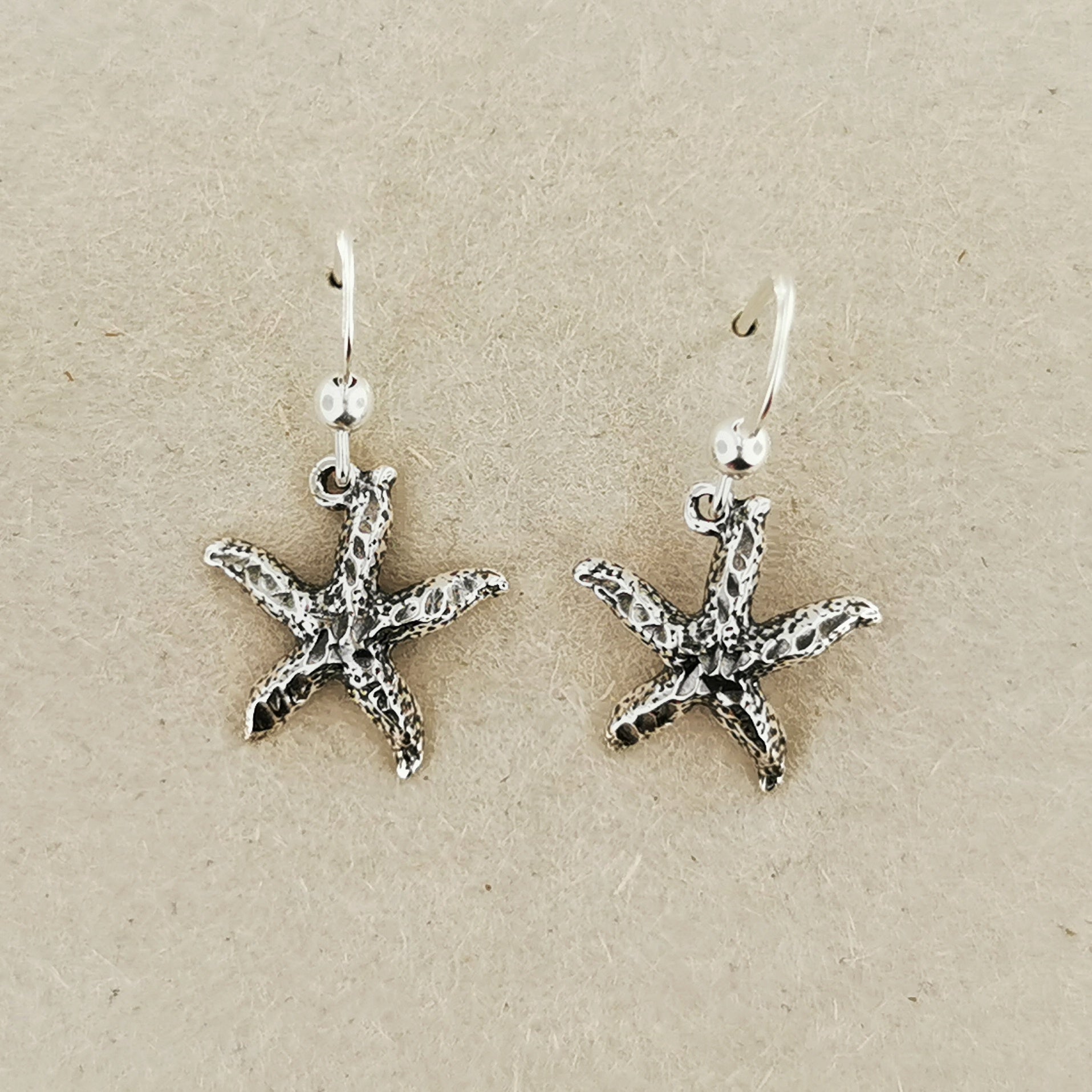 Close-up of silver starfish earrings with beachy charm and style
