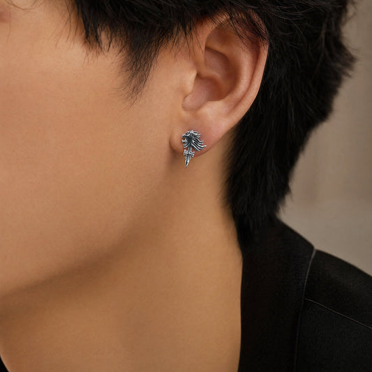 Close-up of an ear wearing a silver earring with a detailed design.
