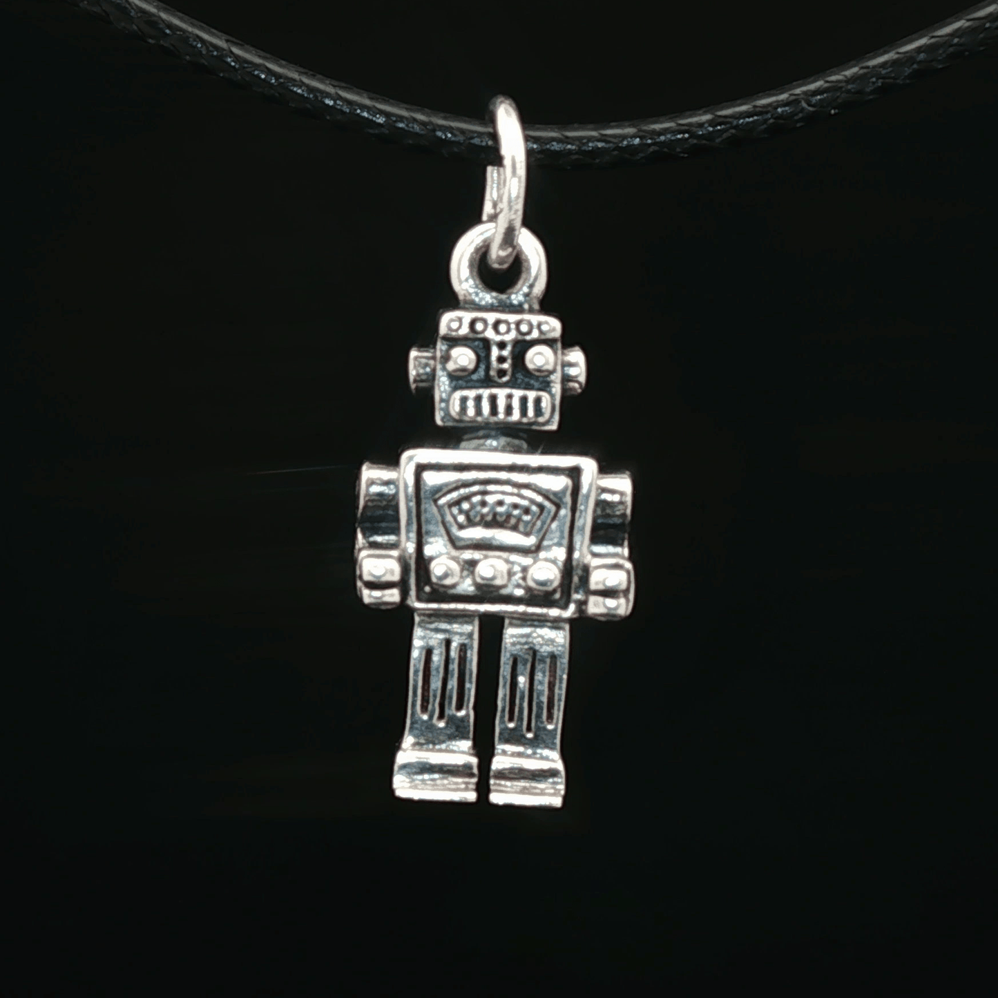 Silver robot pendant on a black cord against a black background