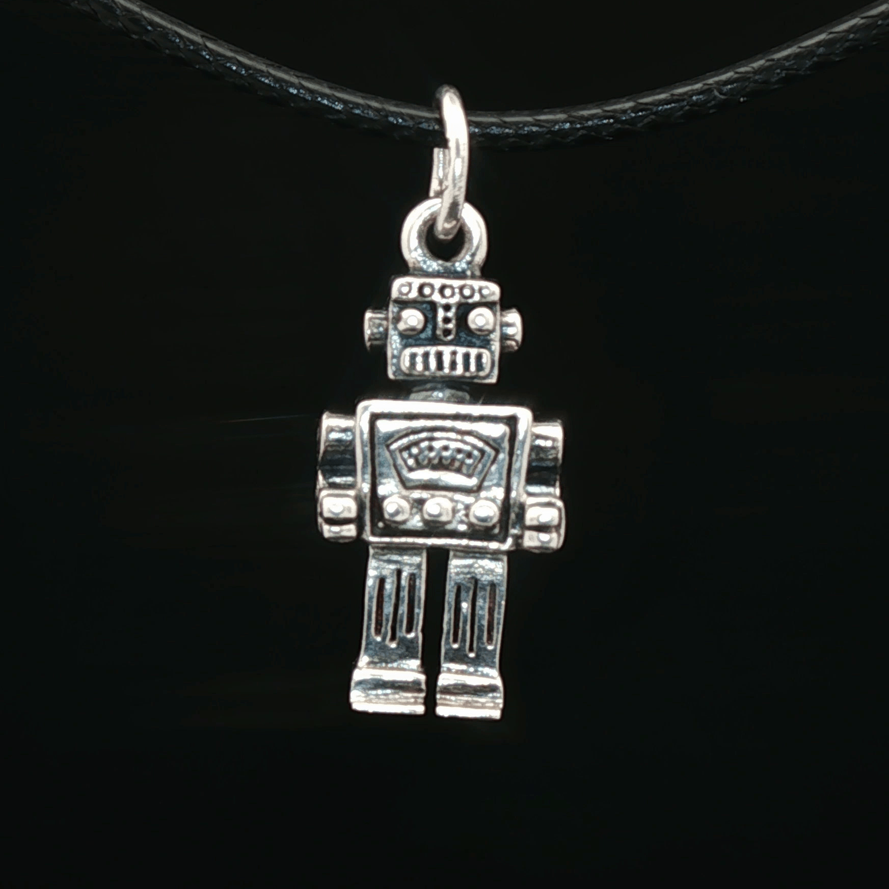 Silver robot pendant on a black cord against a black background